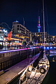 Segelboot im Viaduct Basin mit Bars und beleuchtetem Sky Tower bei Nacht, Auckland, Nordinsel, Neuseeland