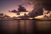 Von La Digue aus sieht man die Sonne hinter der Nachbarinsel Praslin untergehen, La Digue, Praslin, Seychellen, Indischer Ozean, Afrika