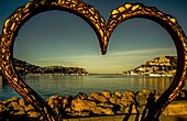  Port d´Andratx, seen in the morning light through the heart-shaped sculpture &quot;Thierro&quot; by Carlos Terroba, Mallorca, Spain 