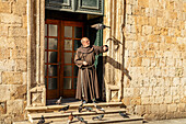  Monk feeding the pigeons in front of the Franciscan monastery Dubrovnik, Croatia, Europe  
