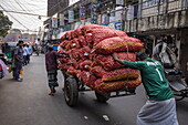 Männer ziehen und schieben einen mit Säcken von Zwiebeln beladenen Wagen durch die Innenstadt von Barisal (Barishal), Bezirk Barisal, Bangladesch, Asien