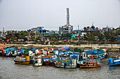 Bunte Fischerboote am Ufer des Mongla-Flusses mit Kommunikationsturm dahinter, Mongla, Bagerhat-Distrikt, Bangladesch, Asien