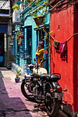  Woman praying in an alley in Kumartuli district with a motorcycle in the foreground, Kolkata, Kolkata, India, Asia 