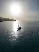  Aerial view silhouette of sailing cruise ship Running on Waves (M&#39;Ocean) anchored in bay at sunrise, Poros, Attica, Greece, Europe 