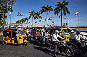  Tuk-tuks and mopeds in rush hour traffic on the road between the Royal Palace and the Mekong, Phnom Penh, Phnom Penh, Cambodia, Asia 