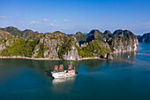 Luftaufnahme des Kreuzfahrtschiffs Ylang (Heritage Line) mit vollen Segeln vor Karstinseln, Lan Ha Bay, Haiphong, Südchinesisches Meer, Vietnam, Asien