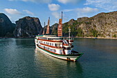 Luftaufnahme des Kreuzfahrtschiffs Ylang (Heritage Line) in einer Bucht vor den Karstinseln, Lan Ha Bay, Haiphong, Südchinesisches Meer, Vietnam, Asien