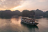 Luftaufnahme des Kreuzfahrtschiffs Ylang (Heritage Line) mit Seekajaks bei Sonnenuntergang, Lan Ha Bay, Haiphong, Südchinesisches Meer, Vietnam, Asien