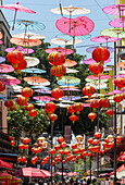 Red paper Chinese lanterns and umbrellas hanging above the street in Chinatown, Mexico City, Mexico advertising various restaurants