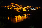 Historic hilltop walled medieval village of Mértola with castle, on the banks of the river Rio Guadiana, Baixo Alentejo, Portugal, Southern Europe nighttime with illumination of orange street lights