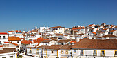 Panoramic style cityscape views over pan tile rooftops and whitewashed buildings in the city centre of Evora, Alto Alentejo, Portugal, southern Europe