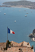  French flag waving in the wind with the blue sea and yachts in the background in Nice, France 