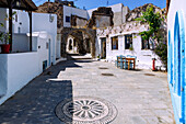 Platz mit Kieselsteinmosaiken, alten Toren, restaurierten Häusern und bewachsenen Bauruinen im Bergdorf Emborió (Emporios, Emporio) auf der Insel Nissyros (Nisyros, Nissiros, Nisiros) in Griechenland