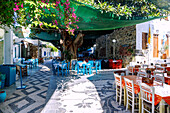 Dorfplatz Platía Ilikioméni mit Tavernen und Baumschatten in Mandráki auf der Insel Nissyros (Nisyros, Nissiros, Nisiros) in Griechenland