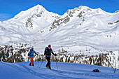 Zwei Personen auf Skitour steigen zur Sattelspitze auf, Rauchkofel im Hintergrund, Sattelspitze, Ahrntal, Naturpark Rieserferner-Ahrn, Zillertaler Alpen, Südtirol, Italien