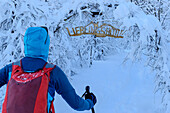  Woman on ski tour walks under arch to Zeller Hütte, Zeller Hütte, Totes Gebirge, Upper Austria, Austria 