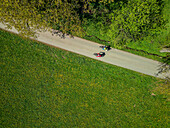 Luftaufnahme mit Mann und Frau fahren auf dem Bodensee-Königssee-Radweg durch Wiesen, Tegernsee, Oberbayern, Bayern, Deutschland