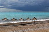 Reihe Sonnenschirme am Strand mit dunklen Gewitterwolken vor der Küste, Dhermi, Albanien, Europa