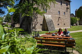 Two cyclists rest at picnic table in moat of Schloss Steinau palace, Steinau an der Straße, Spessart-Mainland, Hesse, Germany