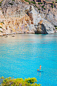 Tourist paddleboarding on the emerald waters of Firopotamos bay, high angle view, Firopotamos, Milos Island, Cyclades Islands, Greece