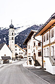  Traditional houses with sgraffiti on facade and church, in Valchava, Winter, Graubünden, Switzerland 