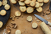  Sablés with walnuts, on tray, grid and wooden board, baked and in process 