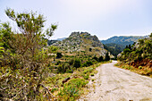  Mountain road to Paleo Pyli (Palio Pili, Palea Pyli, Alt-Pyli, Old Pyli) and view of the castle ruins of Castro, located on a high rock, on the island of Kos in Greece 