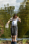 Anonymous woman walking a flooded boardwalk in the Mastbos, a small forest located on the edge of Breda, the Netherlands.