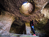 tourist observing a skylight, necropolis, Cala Morell, Ciutadella, Menorca, Balearic Islands, Spain