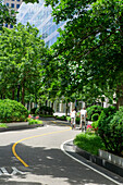  Rückansicht eines Paares, einer mit kleinem Kind, das Fahrrad auf einem Radweg fährt, im Hintergrund die 200 West Street, New York City, New York, USA 