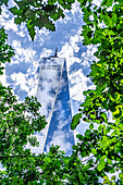  One World Trade Center, Untersicht, Gebäudeaußenseite umgeben von Bäumen vor Wolken und blauem Himmel, New York City, New York, USA 