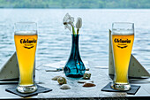  Set table with two glasses of wheat beer and Lake Millstatt in the background, Bar 4613, Millstätt, Via paradiso, Lake Millstatt, Nockberge, Niedere Tauern, Carinthia, Austria 