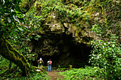 Hikers in front of a Mayan ritual cave, cloud forest on the slopes of Tolimán volcano, Lake Atitlán, Guatemala, Central America