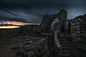  Ruins and archway of Groznez Castle on the cliffs. Sunset and gap in the clouds 