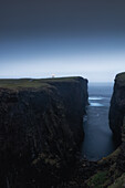 Hohe Klippen am Meer mit Leuchtturm in der Abenddämmerung, Eshaness, Mainland, Shetland Islands, Schottland, Großbritannien