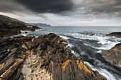  Rocky coast at Burravoe. Dark rain clouds. 