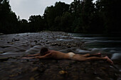 A man enjoying a naked water massage in a tranquil submerged river.