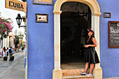 young woman standing at the entrance of a cafe in downtown colonial walled city, Cartagena, Colombia, South America