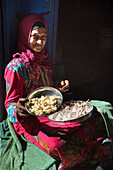 Woman sitting on her doorstep peeling garlic, village of Ramadi, west bank of the Nile south of Edfu, Egypt, North East Africa