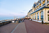 Strandpromende (Promenade Marcel Proust) mit Grand Hotel (Le Grand Hôtel) und Strandblick bei Sonnenuntergang im Abendlicht in Cabourg an der Blumenküste (Côte Fleurie, Cote Fleurie) im Département Calvados in der Region Normandie in Frankreich