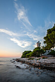 Insel Vir, Leuchtturm und Pinienwald mit Blick über die Küste auf das Gebäude und den Sonnenuntergang, Dalmatien, Kroatien, Adria, Mittelmeer