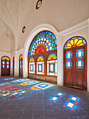 Room with colorful stained glass windows in the Tabatabaei House, a historic mansion built around 1880 in Kashan, Iran.