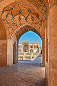  Blick durch die Bögen des Hauptgebäudes auf das Haupteingangstor der Agha-Bozorg-Moschee aus dem 18. Jahrhundert. Kashan, Iran. 