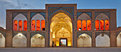  Panoramablick auf das Haupteingangstor der Agha-Bozorg-Moschee aus dem 18. Jahrhundert, beleuchtet in der Abenddämmerung. Kashan, Iran. 