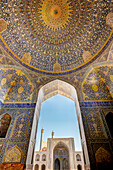 Courtyard view of the Shah Mosque (Masjed-e Shah) from the main prayer hall with its ornate tiled ceiling. Isfahan, Iran.