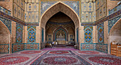 Panoramic interior view of the Hakim Mosque with ornate tiled mosaics on its brick walls and carpeted floor. Isfahan, Iran.