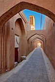 A narrow street with arches above in the historical Old City of Yazd, Iran.