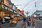 Cycle rickshaw drives in Malioboro Street at dusk. Yogyakarta, Java, Indonesia.