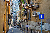 People walk along a narrow street in the historic centre of Macau city, China.