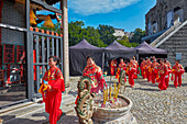 Local women wearing red traditional costumes walk by the Na Tcha Temple. Macau, China.